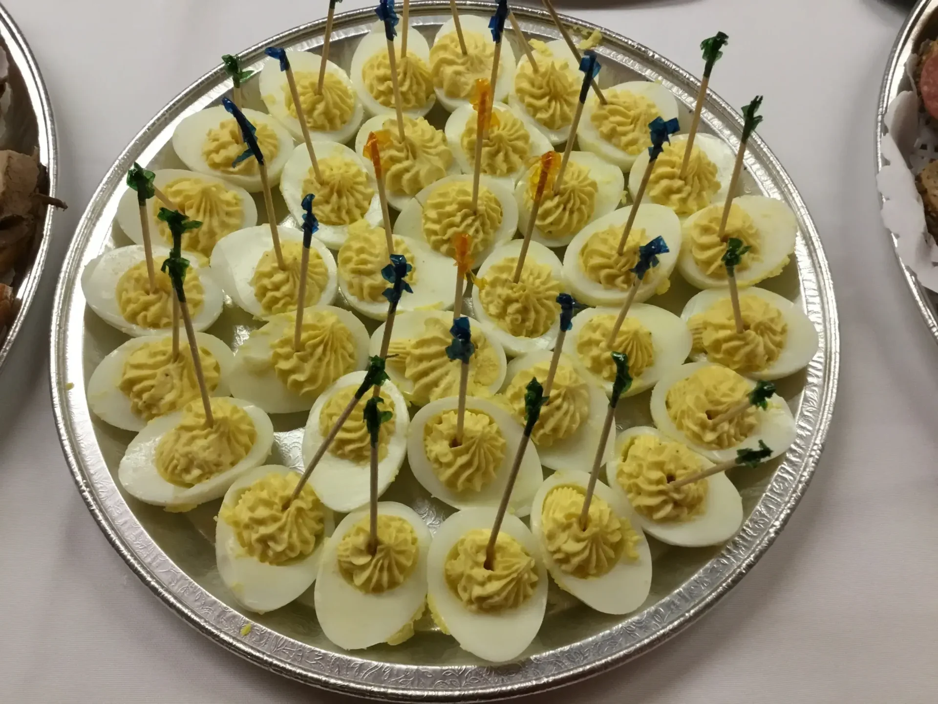 A tray of deviled eggs with toothpicks on top.