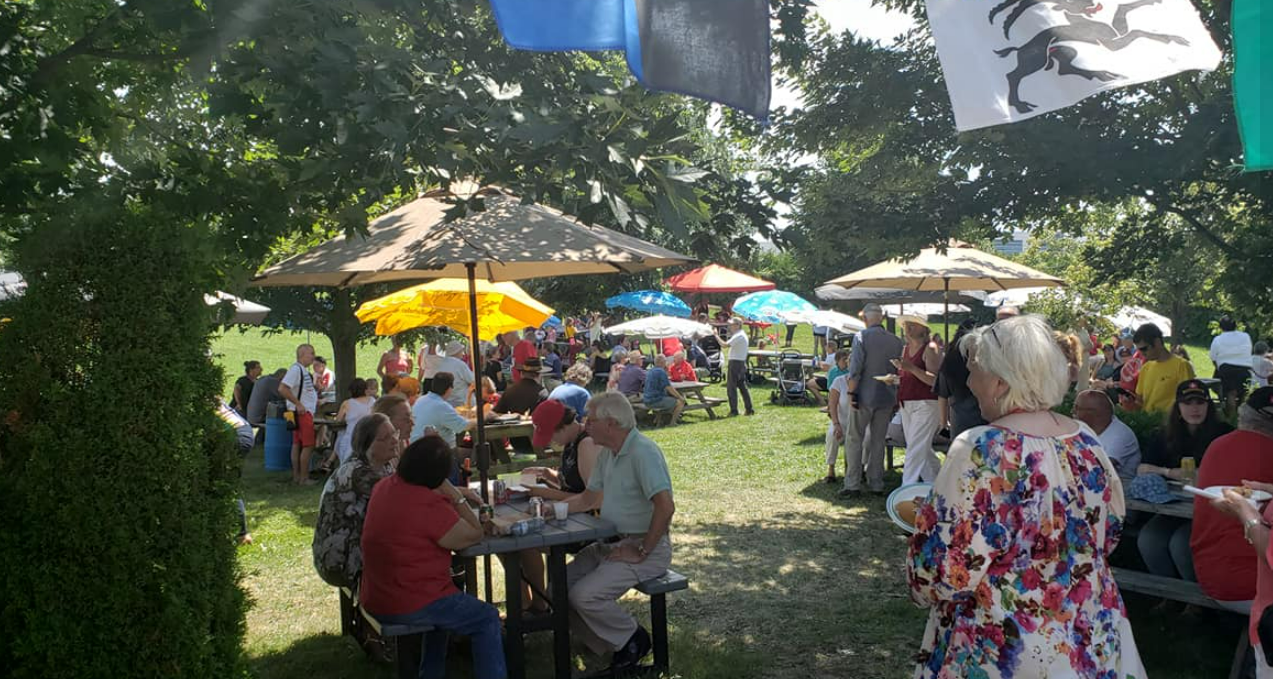 Outdoor picnic with many people under umbrellas.